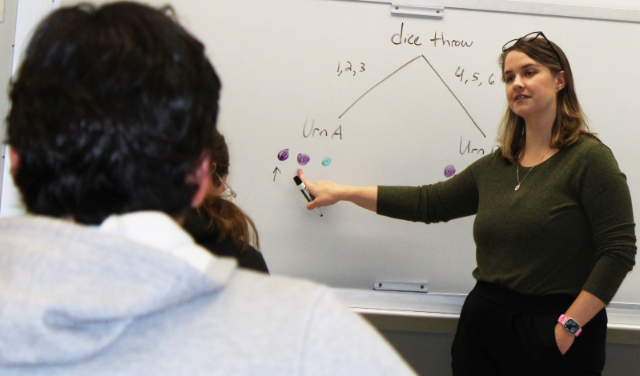 Professor standing in front of whiteboard.