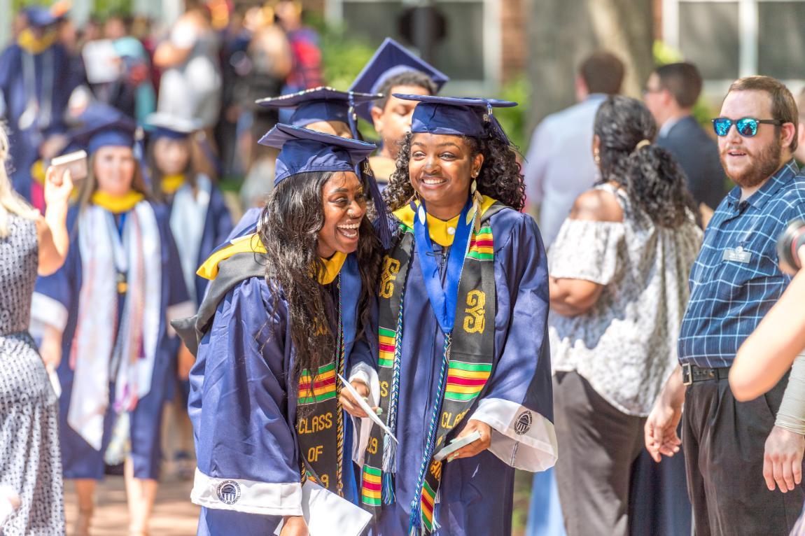 Two students hugging and laughing during Commencement